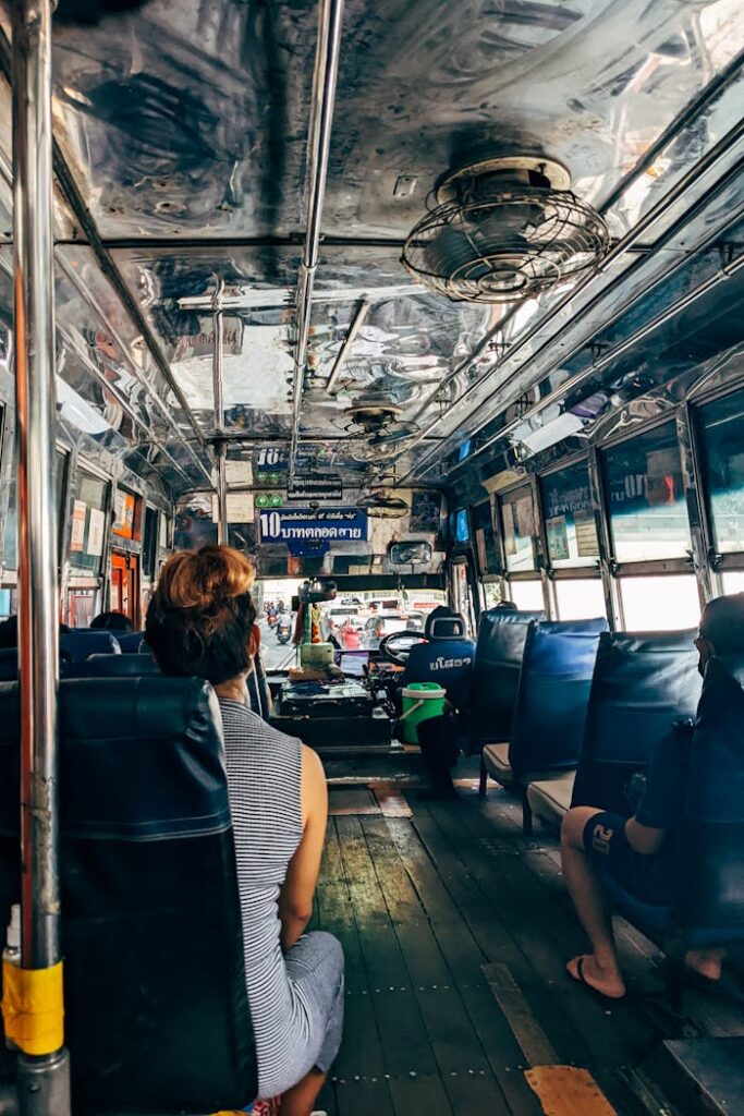 Passengers sit inside a vintage city bus with reflective metal ceiling, capturing a daily commute.