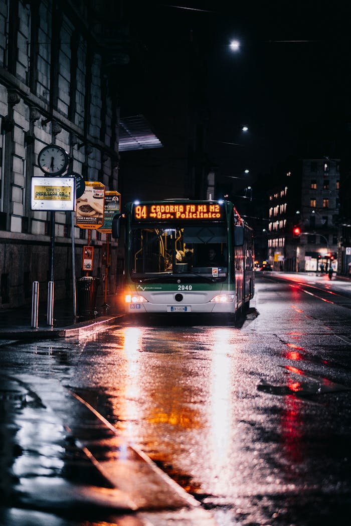 A public bus under streetlights on a wet city street at night.